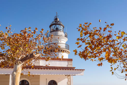 Faro del hotel Tr3sor con follaje otoñal contra cielo azul despejado en España