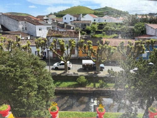 Pátio de vila pitoresco com construções tradicionais portuguesas, rio e colinas verdejantes na Vila Sereia Dourada