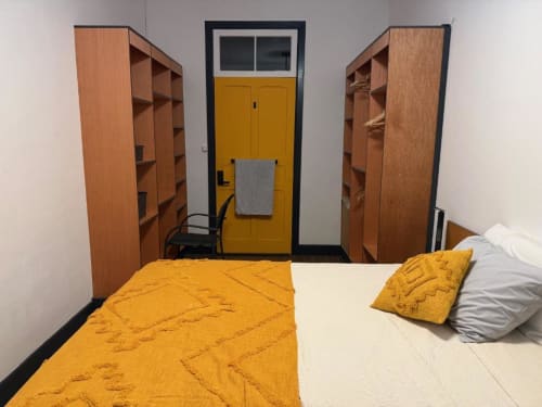 Bright double bedroom with yellow door, wooden wardrobes, and colorful bedding at Golden Mermaid Villa