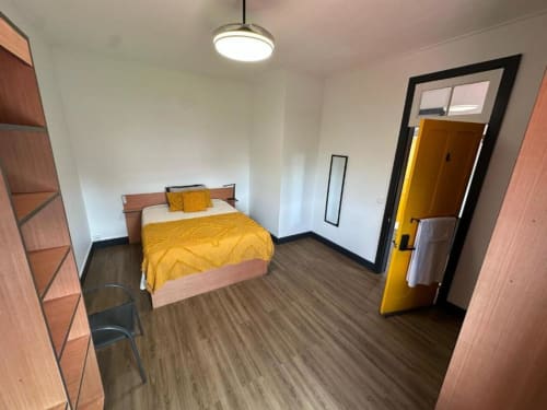 Cozy double bedroom at Golden Mermaid Villa with yellow bedding, wooden furniture, and garden view door in Portuguese B&B