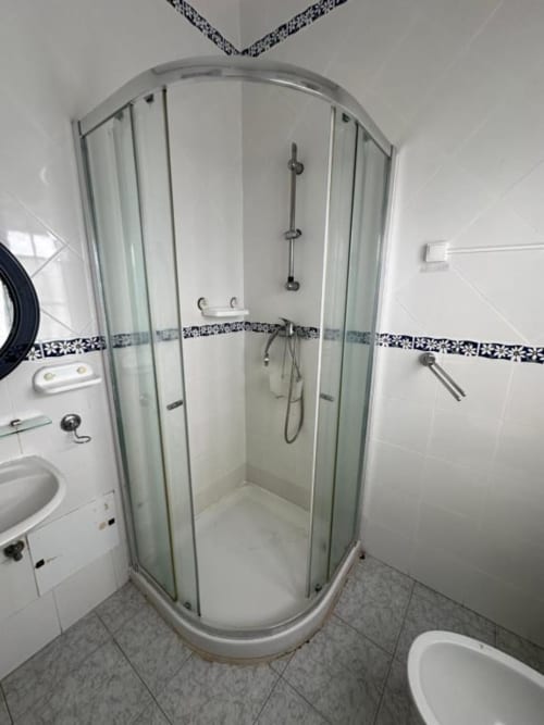 Chuveiro moderno com portas de vidro em banheiro compartilhado da Pousada Golden Mermaid, uma casa de hóspedes portuguesa