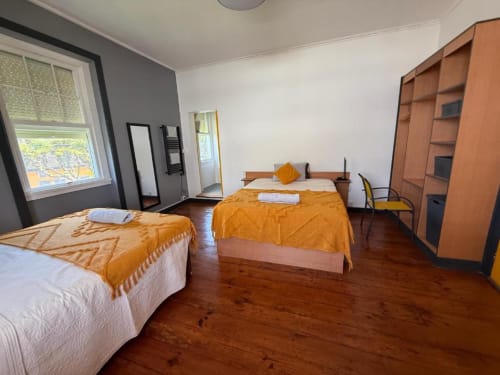 Espaçoso Studio Deluxe com duas camas na Golden Mermaid Villa, piso de madeira e roupa de cama laranja em Portugal