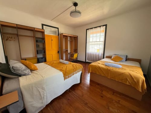 Deluxe Double Studio at Golden Mermaid Villa featuring two beds with golden throws, wooden floors, and bright natural light