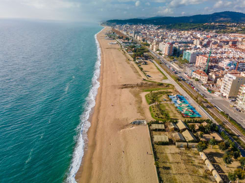 Vista aérea de la ubicación frente al mar del hotel Tr3sor en España con playa de arena, Mar Mediterráneo y ciudad costera