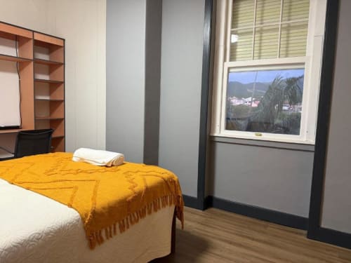 Quarto duplo na Villa Golden Mermaid com colcha amarela, janela com vista para o jardim, mesa de madeira e paisagem de montanha visível