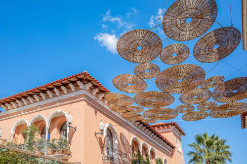 Patio del hotel Tr3sor con toldo de parasol tejido bajo cielo azul y edificio con techo de terracota