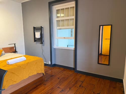 Quarto moderno da Golden Mermaid Villa com roupa de cama amarela, piso de madeira e vista do terraço para pontos turísticos em Portugal