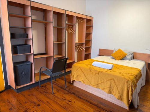 Golden Mermaid Villa double room with yellow bedding, wooden desk, and built-in storage shelving in Portugal