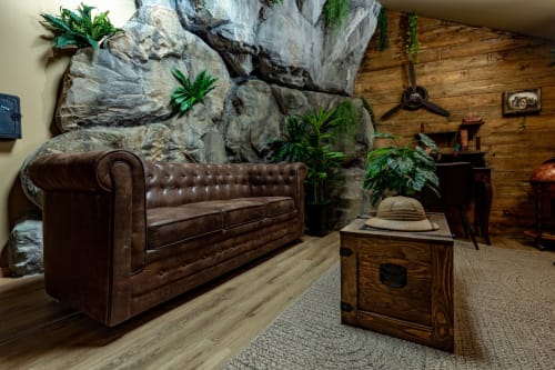 L'appartement L'Incroyable Aventure d'Escape Hotel propose un canapé Chesterfield en cuir, un mur d'escalade et du mobilier en bois