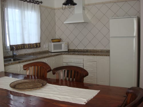 Modern kitchen with white cabinets, granite countertop, and dining area in Villa 2 at Villas del Mar, Puerto Calero