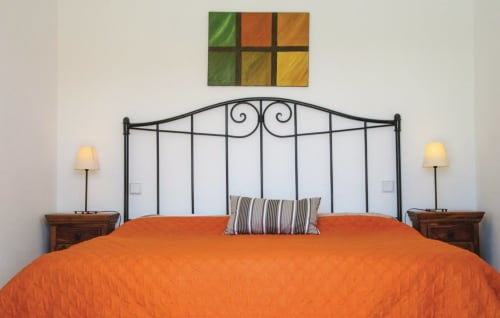 Modern bedroom with orange bedding and wrought iron headboard at Villas del Mar, Puerto Calero