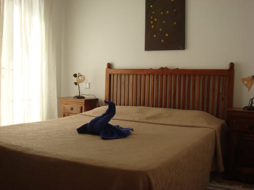 Spacious villa bedroom at Villas del Mar with wooden bed frame, beige bedding, and mountain view in Puerto Calero