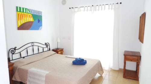 Bright villa bedroom at Villas del Mar with wrought iron bed, colorful art, and mountain views in Puerto Calero