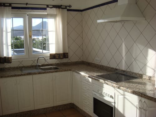 Modern kitchen in Villa 5 at Villas del Mar with granite counters, white cabinets, and mountain views of Puerto Calero