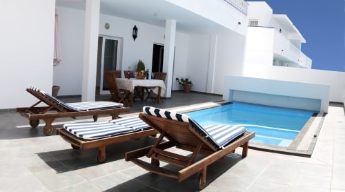 Sunny villa terrace at Villas del Mar with lounge chairs, small pool, and white architecture overlooking Puerto Calero