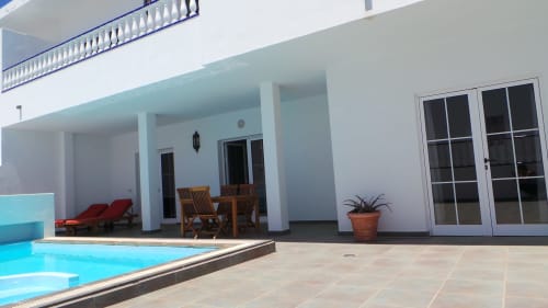 Villa 8 poolside terrace with lounge chairs, wooden seating, and mountain views in Puerto Calero, Las Palmas