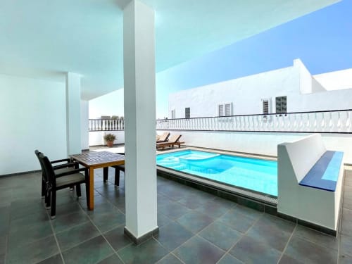 Villas del Mar Villa 8 indoor pool with white columns, lounge chairs, and mountain views in Puerto Calero