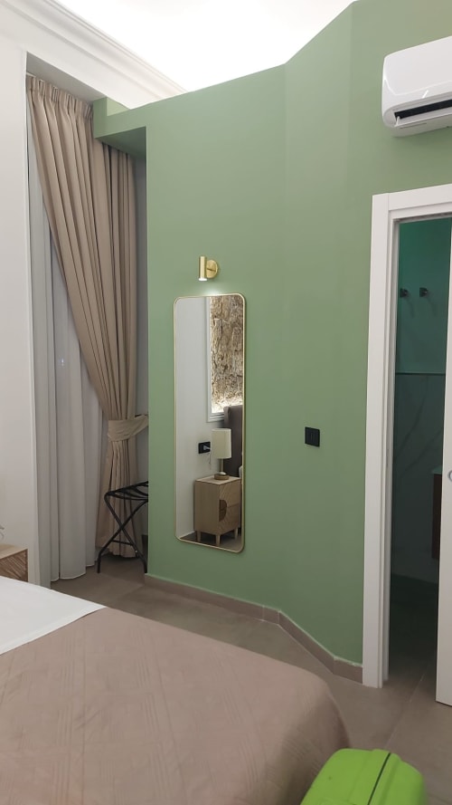 Camera da letto moderna e verde presso Pignasecca Domus Napoli con specchio, tende, climatizzatore e porte con cornici bianche