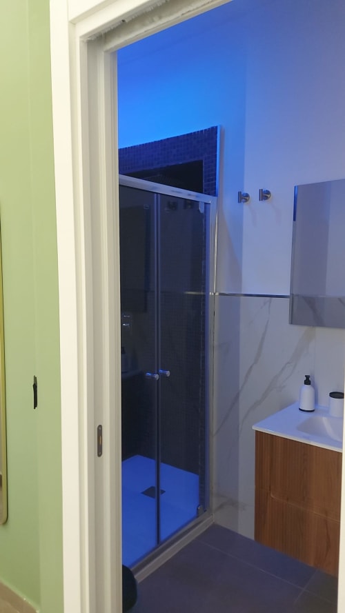 Moderna suite bagno con illuminazione blu, doccia walk-in e vanity in marmo presso Pignasecca Domus a Napoli