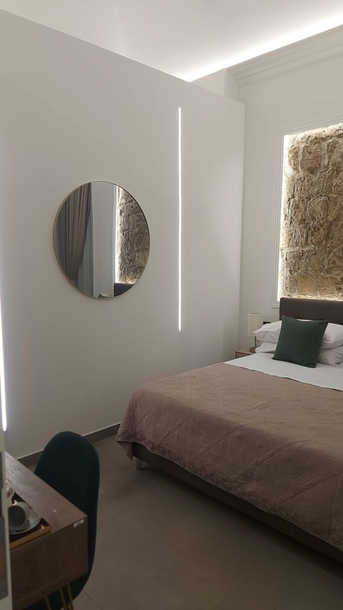 Camera moderna a Pignasecca Domus Napoli con specchio circolare, illuminazione LED lineare e parete in pietra