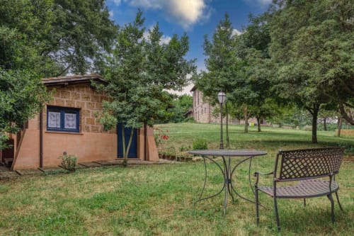 Accogliente cottage in mattoni con porta blu presso Donkeys & Roses a Viterbo, circondato da giardini verdi e sedute all'aperto.