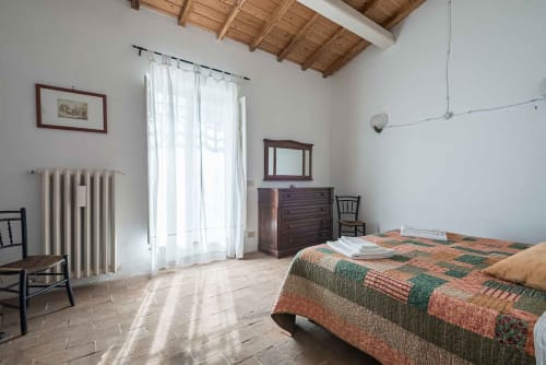 Spaziosa camera da letto presso Donkeys & Roses a Viterbo con trapunta patchwork, mobili in legno e luce naturale dalle finestre