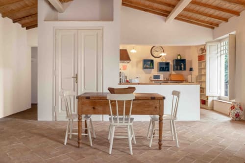 Luminosa zona living open-plan a Donkeys & Roses di Viterbo con tavolo in legno, sedie bianche, cucina e travi rustiche