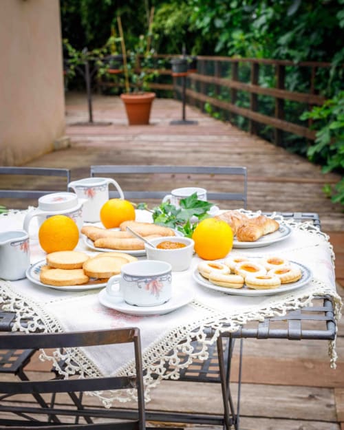 Colazione all'aperto sul terrazzo in legno di Donkeys & Roses con pasticcini, arance, caffè e vista sul giardino a Viterbo,