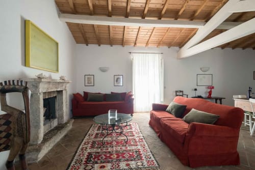 Ampio soggiorno dell'appartamento Donkeys & Roses a Viterbo con divani rossi, camino, travi in legno e luce naturale