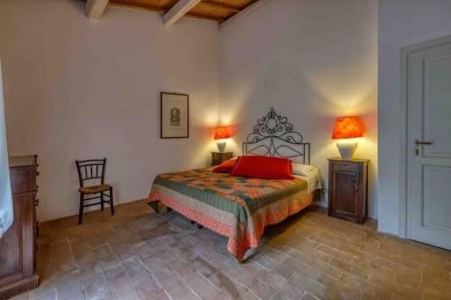 Camera rustica presso Donkeys & Roses a Viterbo con letto in ferro battuto ornamentale, pavimento in terracotta e illuminazione calda