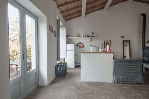 Moderna cucina e zona living nell'appartamento Donkeys & Roses a Viterbo, con mobili bianchi, travi in legno e accesso alla terrazza