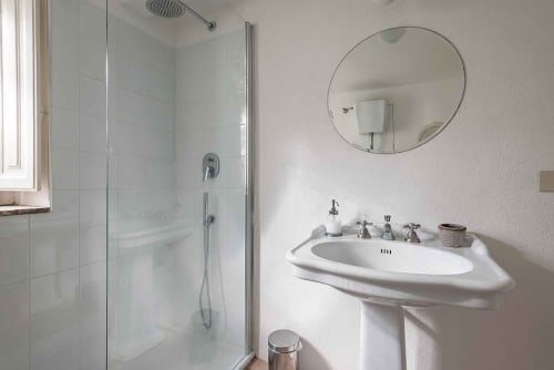 Bagno moderno a Donkeys & Roses a Viterbo con lavabo a colonna, specchio rotondo e doccia in vetro