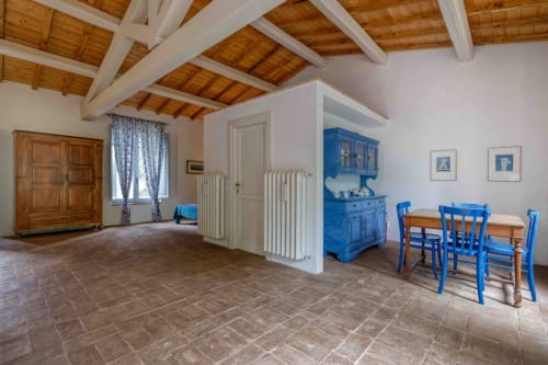 Spazioso interno dell'appartamento presso Donkeys & Roses con mobili blu, travi in legno, piastrelle in terracotta e zona pranzo