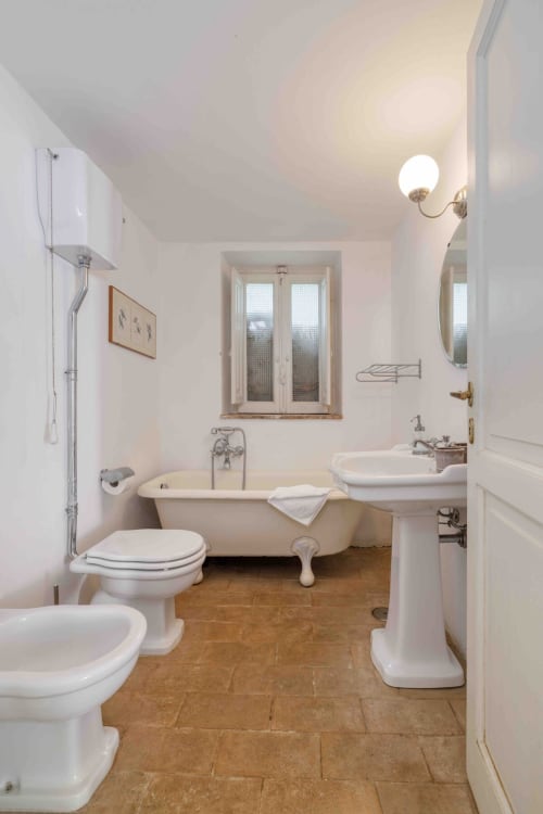 Bagno spazioso a Donkeys & Roses con vasca con piedini, lavabo su colonna, wc e pavimento in legno