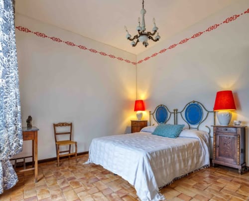 Camera elegante presso la fattoria Donkeys & Roses di Viterbo con letto ornato, lampade rosse, lampadario e arredamento tradizionale