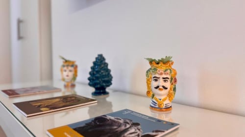 Teste in ceramica siciliana decorativa e riviste sulla scrivania dell'appartamento di Palermo con vista sul mare