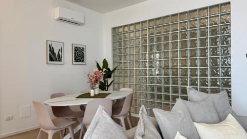 Zona living di moderno appartamento a Palermo con tavolo da pranzo, divano, arte botanica a parete e parete decorativa in vetro verde