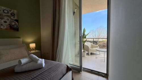 Camera da letto moderna a Palermo con terrazza sul mare, asciugamani bianchi arrotolati sul letto, porte che si aprono all'esterno