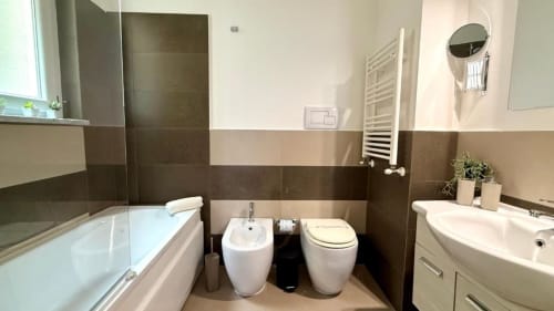 Moderno bagno dell'appartamento di Palermo con vasca, bidet, WC, lavandino, scaldasalviette e rivestimenti in piastrelle marroni