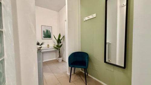 Corridoio del bagno di un moderno appartamento a Palermo con parete accent verde, specchio, sedia turchese e sanitari bianchi