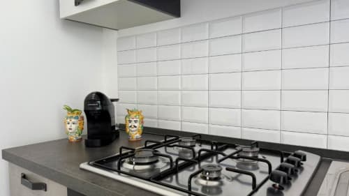 Cucina moderna con piano cottura a gas, macchina caffè nera e teste di moro decorative in appartamento palermitano