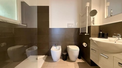 Bagno moderno nell'appartamento di Palermo con doppio lavabo, bidet, WC e finiture in piastrelle scure