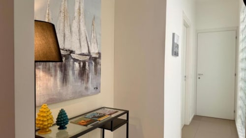 Corridoio di moderno appartamento a Palermo con quadro di barca a vela, alberi decorativi e consolle minimalista vicino alle porte d'ingresso