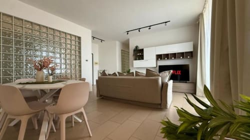 Moderno appartamento a Palermo con 2 camere, divano beige, zona pranzo, cucina e parete in blocchi di vetro