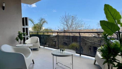 Terrazza moderna con sedute bianche, piante in vaso e vista sul panorama di Palermo e il mare da appartamento con 2 camere.