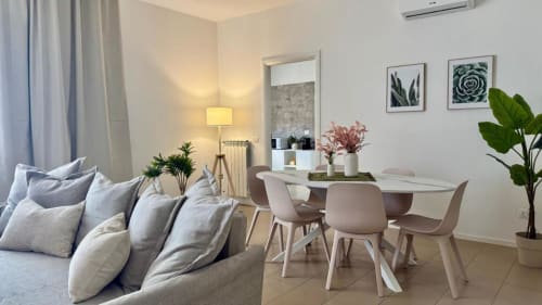 Suite moderna di Palermo con divano grigio, tavolo da pranzo, opere d'arte, piante in vaso e illuminazione calda