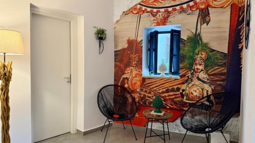 Zona living di moderno appartamento a Palermo con sedie in filo nero, arazzi decorativi asiatici e vista sui landmark della città