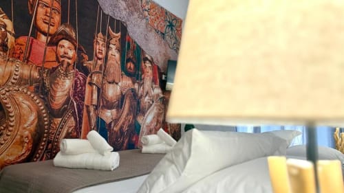 Camera da letto dell'appartamento a Palermo con murale ornamentale, asciugamani arrotolati bianchi e vista sulla città dal balcone