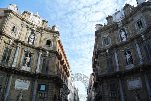 Suggestiva via storica di Palermo con eleganti edifici barocchi e arco decorativo, vista caratteristica dall'appartamento Location 10 Agency