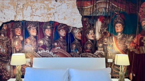 Camera da letto elegante con testiera murale medievale ornamentale a Palermo, cuscini blu e lampade da comodino